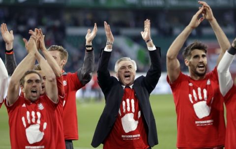 Bayern's head coach Carlo Ancelotti, center, and the players celebrate winning the German soccer champion title after the Bundesliga soccer match against VfL Wolfsburg in Wolfsburg, Germany, Saturday, April 29, 2017. (AP Photo/Michael Sohn)