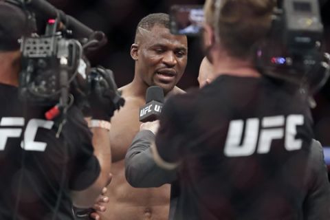 Francis Ngannou, center, is interviewed after winning a UFC 249 mixed martial arts bout against Jairzinho Rozenstruik, Saturday, May 9, 2020, in Jacksonville, Fla. (AP Photo/John Raoux)
