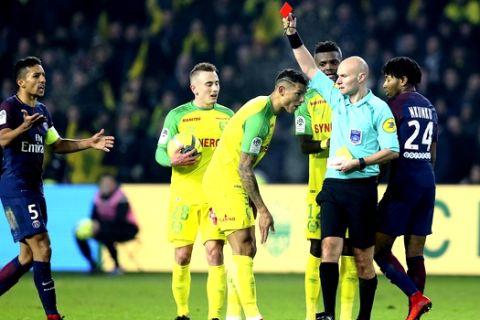 Referee Tony Chapron gives a red card to Nantes defender Diego Carlos, left, after Carlos inadvertently clipped the referee's heels during the French League One soccer match between Nantes and Paris Saint Germain, in Nantes, western France, Sunday, Jan. 14, 2018. French official Tony Chapron kicked out in retribution at Nantes defender Diego Carlos during a league game on Sunday, and then promptly showed Carlos a red card. (AP Photo/David Vincent)