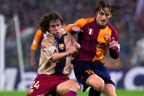 Roma's Francesco Totti, right, is tackled by Barcelona's Carles Puyol during the Champions League soccer match between Roma and Barcelona at Rome's Olympic stadium, Tuesday, Feb. 26, 2002. Roma won 3-0. (AP Photo/Domenico Stinellis)