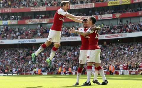 Arsenal's Nacho Monreal, left, celebrates scoring his side's first goal of the game with team mates during the English Premier League soccer match against West Ham United at the Emirates Stadium in London, Sunday April 22, 2018. (Mark Kerton/PA via AP)