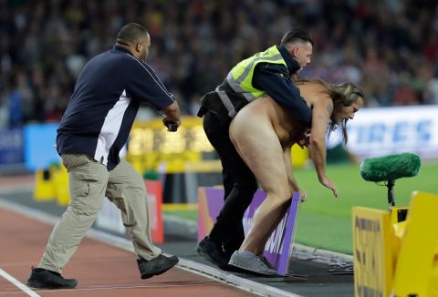 A streaker is apprehend by security after he ran on the track during the World Athletics Championships in London, Saturday, Aug. 5, 2017. (AP Photo/David J. Phillip)