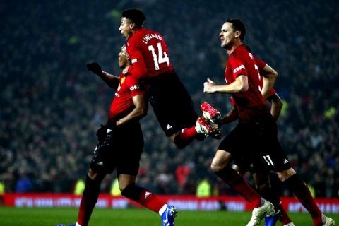 Manchester United's midfielder Jesse Lingard, center, jumps on the shoulders of teammate Anthony Martial who scored his side's first goal during the English Premier League soccer match between Manchester United and Arsenal at Old Trafford stadium in Manchester, England, Wednesday Dec. 5, 2018. (AP Photo/Dave Thompson)