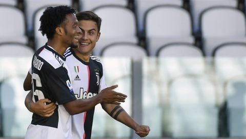 Juventus' Juan Cuadrado, left, celebrates with his teammate Paulo Dybala after scoring his side's 2nd goal, during the Serie A soccer match between Juventus and Torino, at the Allianz Stadium in Turin, Italy, Saturday, July 4, 2020. (Marco Alpozzi/LaPresse via AP)