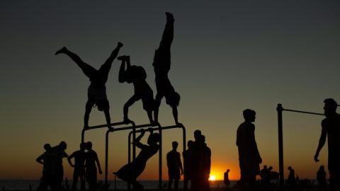 Men exercise in a public gym as the sun sets at the Victoria beach in Cadiz, Spain, Monday, Aug. 13, 2018. (AP Photo/Francisco Seco)
