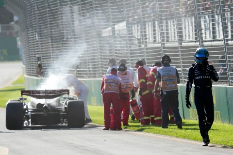 Mercedes driver George Russell of Britain, right, walks to pit lane as course marshals extinguish an engine fire in his car during the Australian Formula One Grand Prix at Albert Park in Melbourne, Sunday, April 2, 2023. (Simon Baker/Pool via AP)