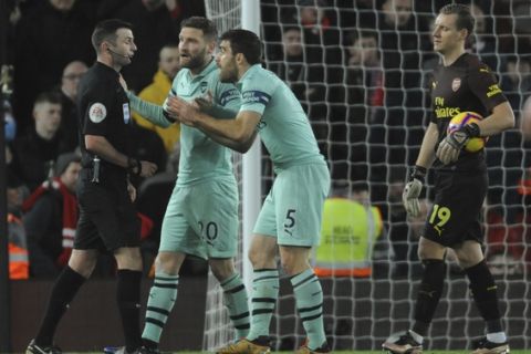 Referee Michael Oliver, left, is pursued by Arsenal's Shkodran Mustafi, centre, and Arsenal's Sokratis Papastathopoulos after Oliver awarded a penalty to Liverpool during the English Premier League soccer match between Liverpool and Arsenal at Anfield in Liverpool, England, Saturday, Dec. 29, 2018. (AP Photo/Rui Vieira)