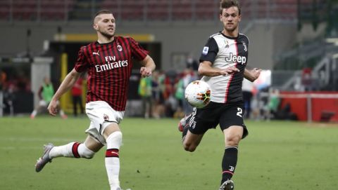 AC Milan's Ante Rebic, left, runs for the ball with Juventus' Daniele Rugani during the Serie A soccer match between AC Milan and Juventus at the San Siro stadium, in Milan, Italy, Tuesday, July 7, 2020. (AP Photo/Antonio Calanni)