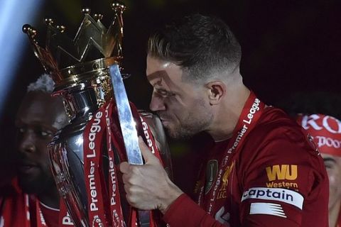 Liverpool's Jordan Henderson kisses the English Premier League trophy after it was presented following the Premier League soccer match between Liverpool and Chelsea at Anfield stadium in Liverpool, England, Wednesday, July 22, 2020. (Paul Ellis, Pool via AP)