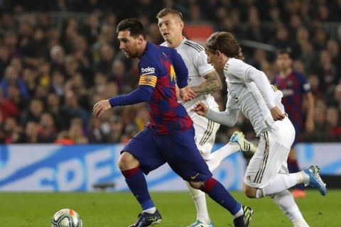 Barcelona's Lionel Messi, left, vies for the ball with Real Madrid's Luka Modric, right, during a Spanish La Liga soccer match between Barcelona and Real Madrid at Camp Nou stadium in Barcelona, Spain, Wednesday, Dec. 18, 2019. Thousands of Catalan separatists are planning to protest around and inside Barcelona's Camp Nou Stadium during Wednesday's "Clasico". (AP Photo/Emilio Morenatti)