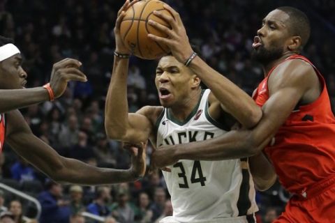 Milwaukee Bucks' Giannis Antetokounmpo, middle, drives to the basket between Toronto Raptors' Pascal Siakam, left, and Serge Ibaka, right, during the second half of an NBA basketball game, Saturday, Jan. 5, 2019, in Milwaukee. The Raptors won 123-116. (AP Photo/Aaron Gash)