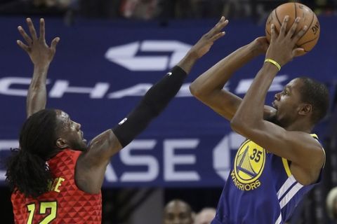 Golden State Warriors forward Kevin Durant (35) shoots against Atlanta Hawks forward Taurean Prince (12) during the first half of an NBA basketball game in Oakland, Calif., Tuesday, Nov. 13, 2018. (AP Photo/Jeff Chiu)
