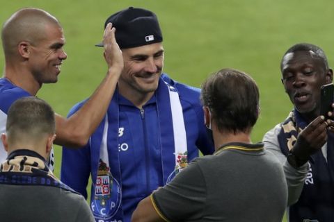 Porto former goalkeeper Iker Casillas, center with hat, joins the players celebrating on the pitch at the end of the Portuguese League soccer match between FC Porto and Sporting CP at the Dragao stadium in Porto, Portugal, Wednesday, July 15, 2020. Porto defeated Sporting 2-0 to clinch the championship with two rounds left to play. (AP Photo/Luis Vieira)