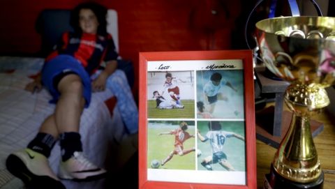 In this Nov. 19, 2016 photo, a framed picture shows Thiago "Coco" Perugini next to images of soccer star Diego Maradona, at his home where he lies on bed, on the outskirts of Buenos Aires, Argentina. Like Maradona, Thiago is a classic playmaker. He knows that he wants to be a professional soccer player. But what would he do, if he doesn't end up going pro? After a long silence, he shrugs his shoulders, smiles and answers: "I don't know." (AP Photo/Natacha Pisarenko)