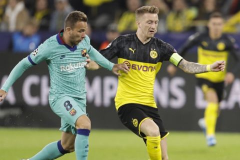 Barcelona's Arthur, left, challenges for the ball with Dortmund's Marco Reus during the Champions League Group F soccer match between Borussia Dortmund and FC Barcelona in Dortmund, Germany, Tuesday, Sept. 17, 2019. (AP Photo/Michael Probst)