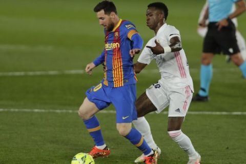 Barcelona's Lionel Messi, left, vies for the ball with Real Madrid's Vinicius Junior during the Spanish La Liga soccer match between Real Madrid and FC Barcelona at the Alfredo di Stefano stadium in Madrid, Spain, Saturday, April 10, 2021. (AP Photo/Manu Fernandez)