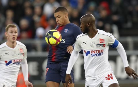 PSG's Kylian Mbappe, centre, and Amiens' Prince-Desir Gouano, right, challenge for the ball during the French League One soccer match between Amiens and Paris-Saint-Germain at the Stade de la Licorne stadium in Amiens, France, Saturday, Jan. 12, 2019. (AP Photo/Christophe Ena)
