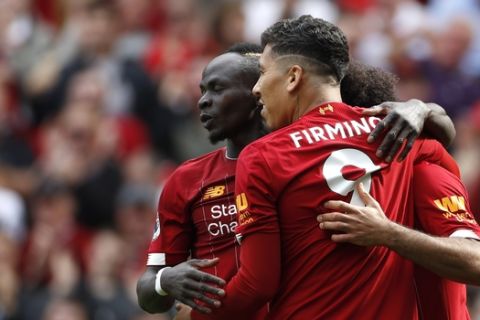 Liverpool's Sadio Mane, left, celebrates with Liverpool's Roberto Firmino, center, and Liverpool's Mohamed Salah, right, after scoring his sides second goal during the English Premier League soccer match between Liverpool and Newcastle at Anfield stadium in Liverpool, England, Saturday, Sept. 14, 2019. (AP Photo/Rui Vieira)