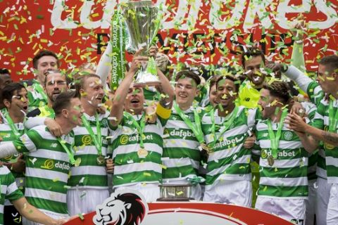 Celtic's Scott Brown, center left, lifts the trophy during the Ladbrokes Scottish Premiership match at Celtic Park, Glasgow, Scotland, Sunday, May 21, 2017. Celtic became the first team in 118 years to complete a season undefeated in Scotlands top division by beating Hearts 2-0 on Sunday. (Craig Watson/PA via AP)