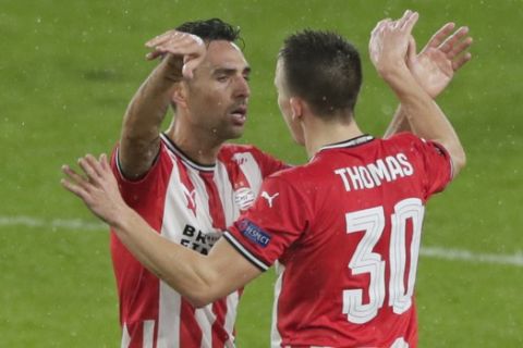 PSV's Ryan Thomas, right, celebrates with PSV's Eran Zahavi who scored his side's first goal during the Europa League round of 32 second leg soccer match between PSV and Olympiacos at the Philips stadium in Eindhoven, Netherlands, Thursday, Feb. 25, 2021. (AP Photo/Peter Dejong)
