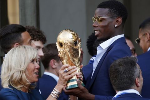 French player Paul Pogba lifts the cup with Brigitte Macron, wife of French President Emmanuel Macron, at the Elysee Palace after the parade down the Champs-Elysees, where tens of thousands thronged after the team's 4-2 victory over Croatia at the Monday, July 16, 2018 in Paris. (AP Photo/Francois Mori)