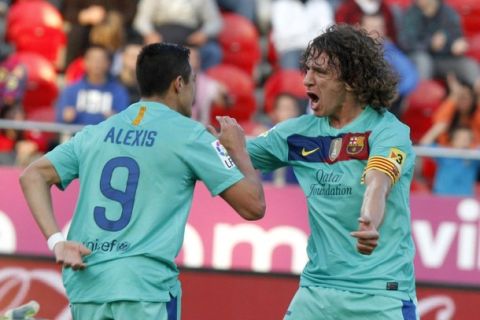 Barcelona's Alexis celebrates his goal with team mate Carles Puyol during their Spanish first division soccer match against Real Mallorca at the Iberostar stadium in Mallorca March 24, 2012.   REUTERS/Enrique Calvo (SPAIN - Tags: SPORT SOCCER)