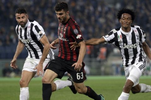 AC Milan's Patrick Cutrone, center, is challenged by Juventus' Andrea Barzagli, left, and Juventus' Juan Cuadrado during the Italian Cup final soccer match between Juventus and AC Milan, at the Rome Olympic stadium, Wednesday, May 9, 2018. (AP Photo/Gregorio Borgia)