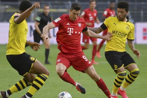 Munich's Robert Lewandowski, center, and Dortmund's Jadon Sancho, right, challenge for the ball during the German Bundesliga soccer match between Borussia Dortmund and FC Bayern Munich in Dortmund, Germany, Tuesday, May 26, 2020. The German Bundesliga is the world's first major soccer league to resume after a two-month suspension because of the coronavirus pandemic. (Federico Gambarini/DPA via AP, Pool)