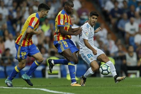 Real Madrid's Marco Asensio, right, vies for the ball with Valencia's Carlos Soler, left, and Antonio Latorre Grueso during a Spanish La Liga soccer match between Real Madrid and Valencia at the Santiago Bernabeu stadium in Madrid, Sunday, Aug. 27, 2017. (AP Photo/Francisco Seco)