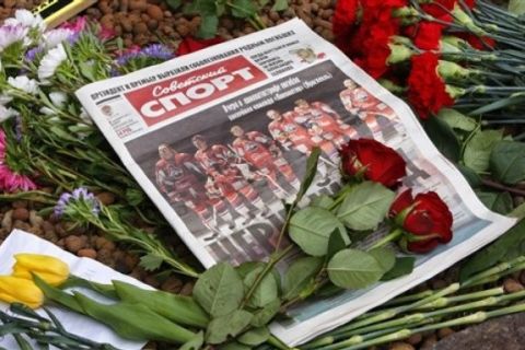 A paper with a photo of the Russian professional hockey team Lokomotiv on the front page, nearly all of whom died in the fatal plane crash lays on a bed of flowers in front of the Czech Embassy in Moscow, Russia, Thursday, Sept. 8, 2011. Among those killed were three Czech stars -- Jan Marek, Josef Vasicek and Karel Rachunek. Investigators on Thursday searched for flight recorders in the shattered remains of an airliner that crashed, killing 43 people including most of one of Russia's premier hockey teams. (AP Photo/Sergei Grits)