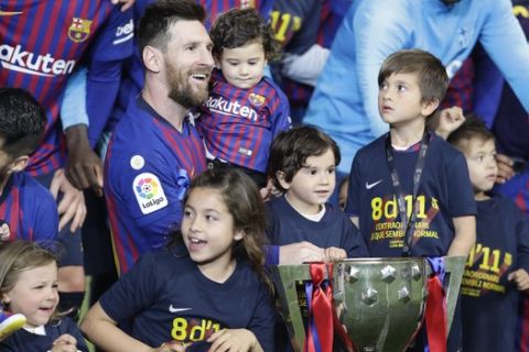 Barcelona forward Lionel Messi with his children pose with the trophy after winning the Spanish League title, at the end of the Spanish La Liga soccer match between FC Barcelona and Levante at the Camp Nou stadium in Barcelona, Spain, Saturday, April 27, 2019. Barcelona clinched the Spanish La Liga title, with three matches to spare, after it defeated Levante 1-0. (AP Photo/Manu Fernandez)