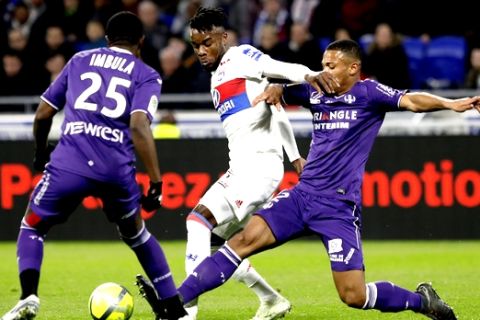 Lyon's Bertrand Traore, center, challenges with Toulouse's Gilbert Imbula Wanga, left, and Kelvin Amian Adou, right, during their French League One soccer match in Decines, near Lyon, central France, Sunday, April 1, 2018. (AP Photo/Laurent Cipriani)