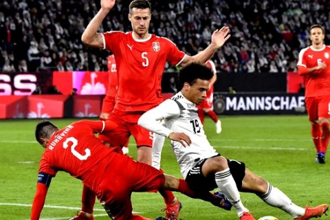 Germany's Leroy Sane, right, duels for the ball with Serbia's Antonio Rukavina, left, and Serbia's Uros Spajic during a international friendly soccer match between Germany and Serbia at the Volkswagen Arena stadium in Wolfsburg, Germany, Wednesday, March 20, 2019. (AP Photo/Martin Meissner)