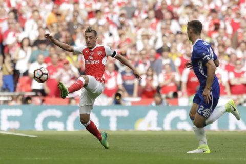 Arsenal's Mesut Ozil, left, controls the ball next to Chelsea's Gary Cahill during the English FA Cup final soccer match between Arsenal and Chelsea at the Wembley stadium in London, Saturday, May 27, 2017. (AP Photo/Matt Dunham)