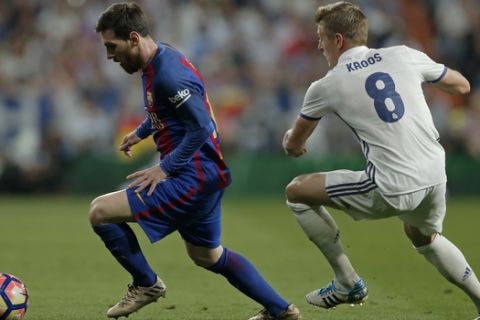 Barcelona's Lionel Messi, left, runs with the ball ahead of Real Madrid's Toni Kroos during a Spanish La Liga soccer match between Real Madrid and Barcelona, dubbed 'el clasico', at the Santiago Bernabeu stadium in Madrid, Spain, Sunday, April 23, 2017. (AP Photo/Daniel Ochoa de Olza)