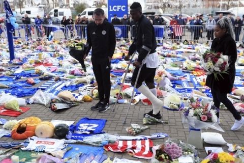 Leicester City player Daniel Amartey, centre, comes to view tributes left by fans and pays his respects at Leicester City Football Club, Tuesday Oct. 30, 2018, to Leicester Chairman, Vichai Srivaddhanaprabha, who died with four others Saturday in a helicopter crash. The flight data recorder from the helicopter that crashed with the Leicester soccer team's owner on board is being examined by investigators. (Mike Egerton/PA via AP)