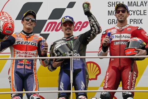 Second placed Spain's Marc Marquez, left, winner Maverick Vinales of Spain, center, and third-placed Andrea Dovizioso of Italy pose for photo after the MotoGP race at the Malaysia Motorcycle Grand Prix at Sepang International circuit in Sepang, Sunday, Nov. 3, 2019. (AP Photo/Vincent Thian)