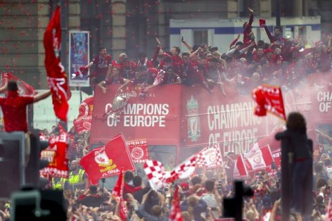 Fans look on as Liverpool's Jordan Henderson holds the trophy, as Liverpool soccer team ride an open top bus during the Champions League Cup Winners Parade through the streets of Liverpool, England, Sunday June 2, 2019.  Liverpool is champion of Europe for a sixth time after beating Tottenham 2-0 in the Champions League final played in Madrid Saturday. (Richard Sellers/PA via AP)