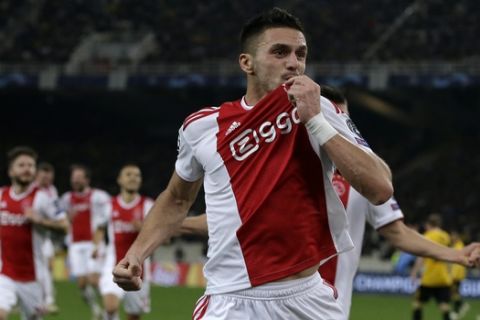 Ajax's Dusan Tadic kisses his jersey as he celebrates after scoring his side opening goal during a Group E Champions League soccer match between AEK Athens and Ajax at the Olympic Stadium in Athens, Tuesday, Nov. 27, 2018. (AP Photo/Thanassis Stavrakis)