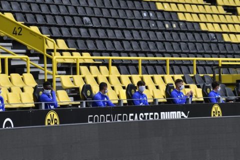 Schalke alternate players sit on the bench during the German Bundesliga soccer match between Borussia Dortmund and Schalke 04 in Dortmund, Germany, Saturday, May 16, 2020. The German Bundesliga becomes the world's first major soccer league to resume after a two-month suspension because of the coronavirus pandemic. (AP Photo/Martin Meissner, Pool)