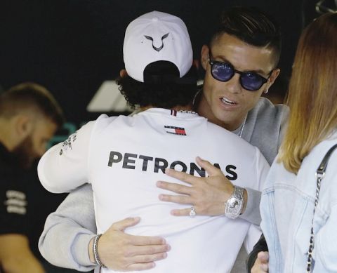 Mercedes driver Lewis Hamilton of Britain, left, hugs with Cristiano Ronaldo at the pit line ahead of the second practice session at the Monaco racetrack, in Monaco, Thursday, May 23, 2019. The Formula one race will be held on Sunday. (AP Photo/Luca Bruno)