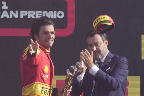 Ferrari driver Carlos Sainz of Spain, left, throws his hat as he celebrates on the podium his third place at the Formula One Italian Grand Prix auto race, at the Monza racetrack, in Monza, Italy, Sunday, Sept. 3, 2023. (AP Photo/Luca Bruno)