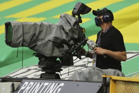 A TV cameraman watches into the camera prior to the start of the English Premier League soccer match between Norwich City and Southampton at Carrow Road in Norwich, England, Friday, June 19, 2020. The English Premier League resumes Wednesday after its three-month suspension because of the coronavirus outbreak. (AP Photo/ Richard Heathcote/Pool)