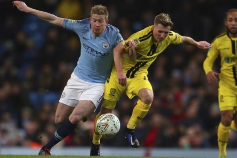 Manchester City midfielder Kevin De Bruyne, left, and Burton Albion's Jamie Allen challenge for the ball during the English League Cup semi-final first leg soccer match between Manchester City and Burton Albion at the Etihad Stadium in Manchester, England, Wednesday, Jan. 9, 2019. (AP Photo/Dave Thompson)