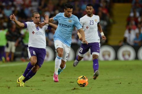 Manchester City's Gael Clichy, center, tries to keep the ball against UAE's Al-Ain club players Yassine El Ghanassy, left, and Mohamed Ahmed during a friendly match in Al Ain, United Arab Emirates, Thursday, May 15, 2014. (AP Photo/ Wael Ladki)-
