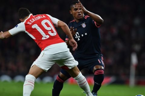 Arsenal's Spanish midfielder Santi Cazorla (L) vies against Bayern Munich's Brazilian midfielder Douglas Costa during the UEFA Champions League football match between Arsenal and Bayern Munich at the Emirates Stadium in London, on October 20, 2015.    AFP PHOTO / BEN STANSALL        (Photo credit should read BEN STANSALL/AFP/Getty Images)