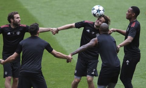 Manchester United's Daley Blind heads a ball while holding hands with Juan Mata, left, and Anthony Martial, right, during a training session at Benfica's Luz stadium in Lisbon, Tuesday, Oct. 17, 2017. Manchester United will face Benfica Wednesday in a Champions League group A soccer match. (AP Photo/Armando Franca)
