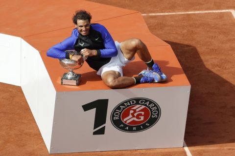 The logo on the podium was altered to read 10 as Spain's Rafael Nadal holds the trophy after winning his tenth French Open title against Switzerland's Stan Wawrinka in three sets, 6-2, 6-3, 6-1, during their men's final match of the French Open tennis tournament at the Roland Garros stadium, in Paris, France, Sunday, June 11, 2017. (AP Photo/Petr David Josek)