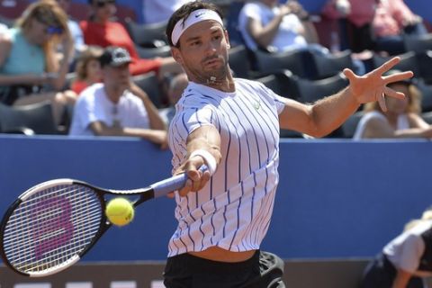 In this photo taken Saturday, June 20, 2020, Grigor Dimitrov from Bulgaria returns the ball to Croatia's Borna Coric during their semifinal match at a tournament in Zadar, Croatia. Dimitrov says he has tested positive for COVID-19 and his announcement led to the cancellation of an exhibition event in Croatia where Novak Djokovic was scheduled to play on Sunday. (AP Photo/Zvonko Kucelin)