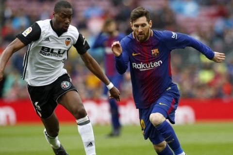 FC Barcelona's Lionel Messi, right, duels for the ball against Valencia's Geoffrey Kondogbia during the Spanish La Liga soccer match between FC Barcelona and Valencia at the Camp Nou stadium in Barcelona, Spain, Saturday, April 14, 2018. (AP Photo/Manu Fernandez)